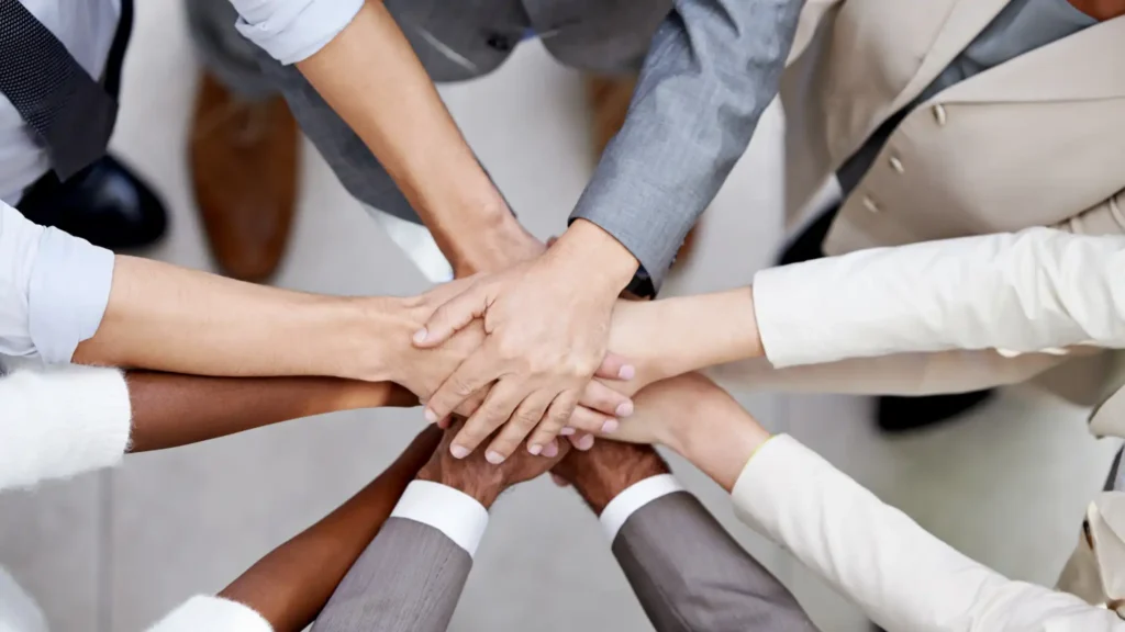 Diverse group of professionals placing their hands together to represent teamwork and collaboration
