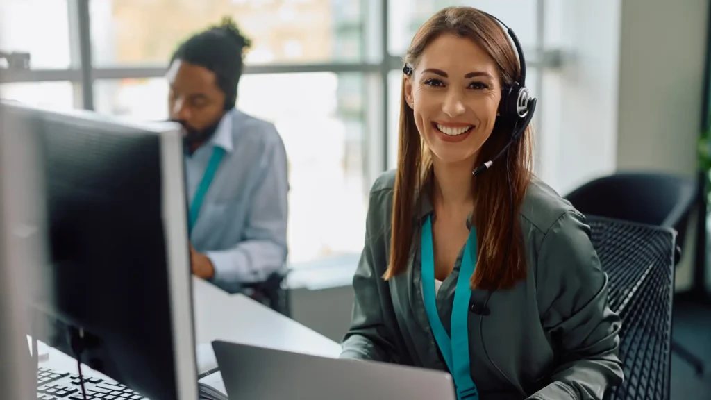 Customer support representative wearing a headset and assisting users at a computer