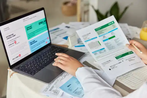 Professional reviewing financial reports and invoices on a laptop, representing bookkeeping and accounting skills.