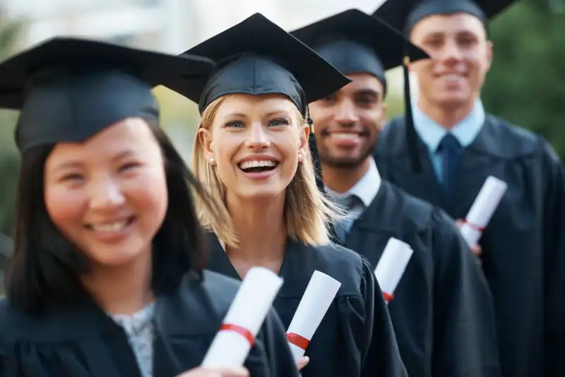 Graduates wearing caps and gowns holding diplomas, representing student achievement and credential completion.